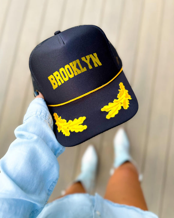 Brooklyn New York black trucker hat with gold varsity lettering, gold rope and gold oak leaves on the visor